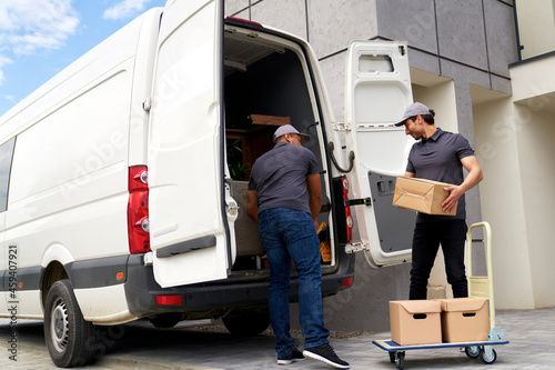 Delivery men loading cardboard box in van photo