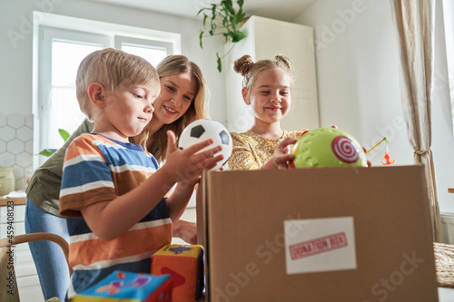 Mother looking at children putting toys in donation box