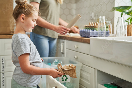 Girl collecting garbage in recycling bin at home