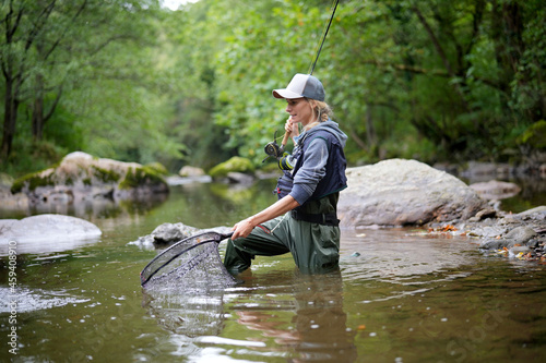 Fotografia young woman fly fishing in a mountain river