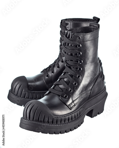 Pair of biker boots made of thick black leather, laced, with a high stylish sole made of automobile rubber with a reinforced front, isolated on a white background. Brutal shoes.