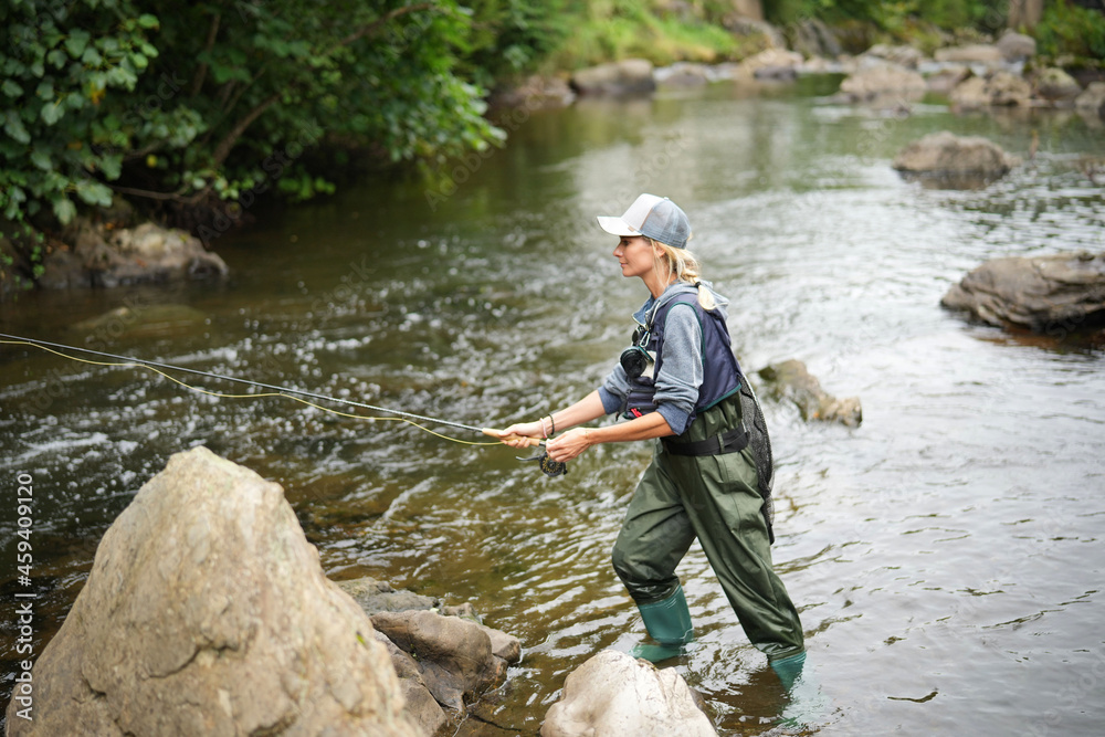 young woman fly fishing in a mountain river young woman fly fishing in a mountain river