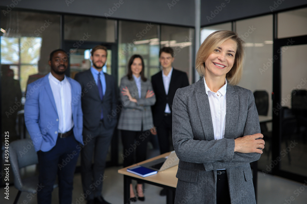 © ty - Business woman with her staff, people group in background at modern bright office indoors.