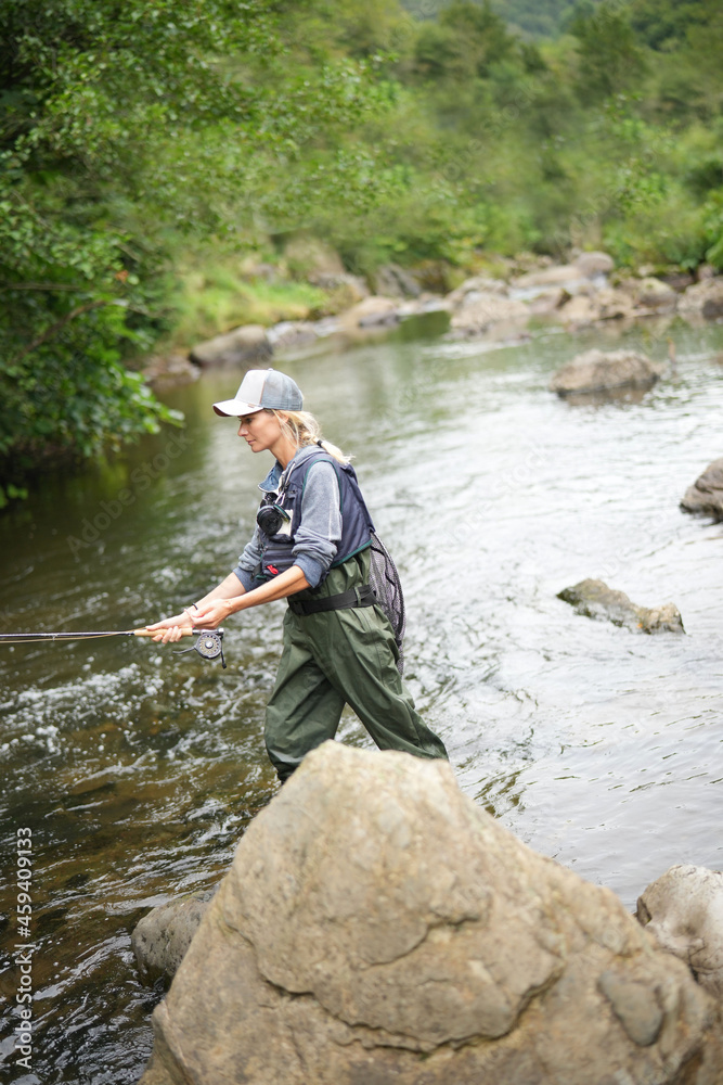 young woman fly fishing in a mountain river young woman fly fishing in a mountain river