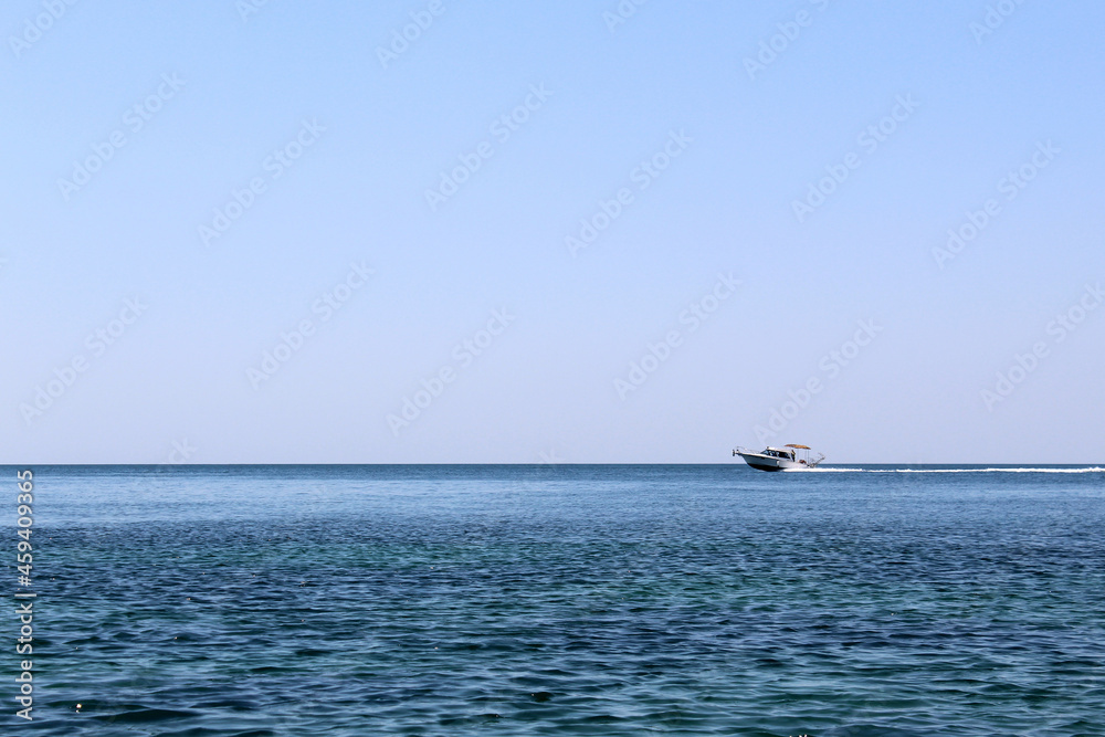 In the distance, a yacht rushes along the sea at high speed.