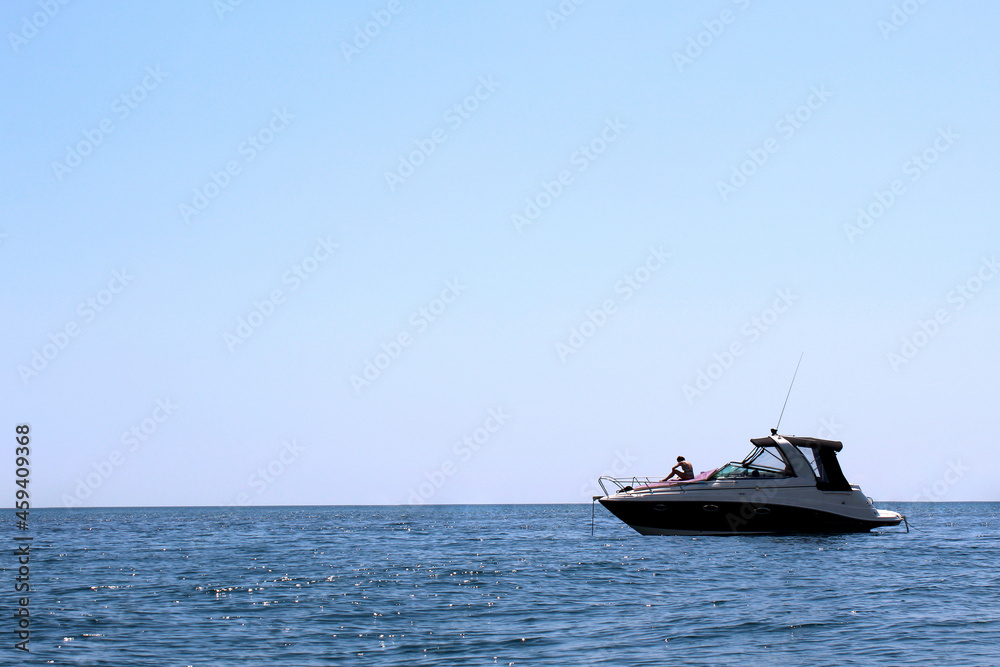 A young girl sunbathes on a yacht moored in the sea.