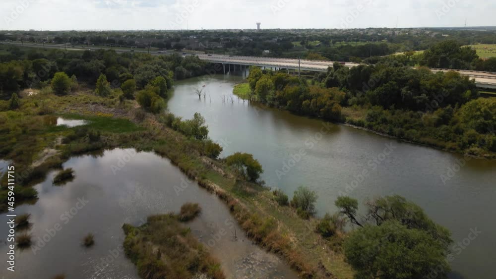 Aerial birdseye view of river flowing under highway bridge, drone 4K