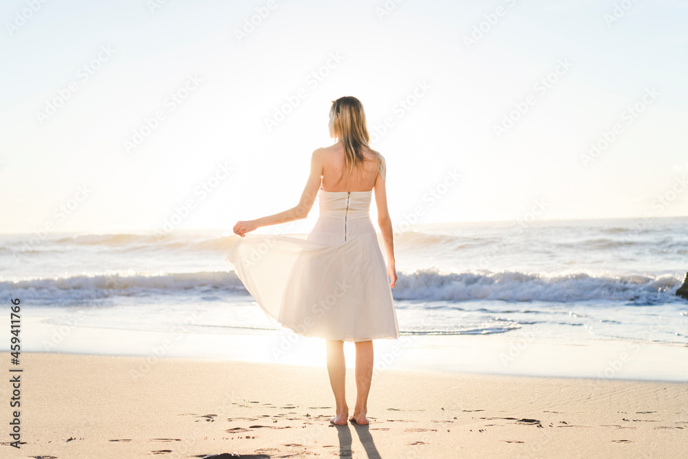 Young bride in wedding dress standing on beach Young bride in wedding dress standing on beach