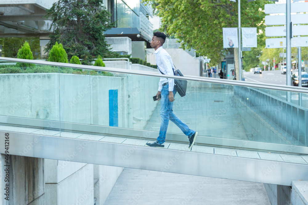 young black business man walking on a glass bridge