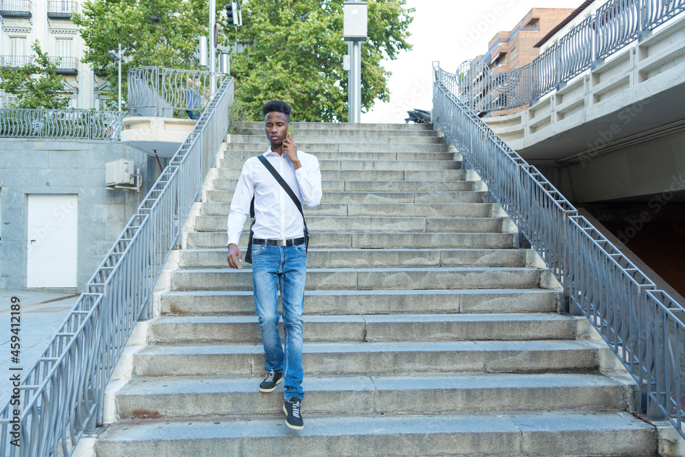 young black businessman with briefcase walking down stairs and talking on the phone