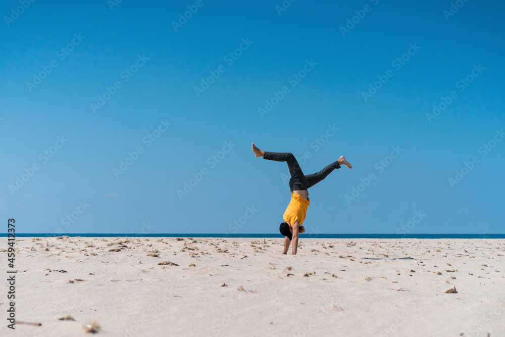 Man doing handstand on beach during sunny day Man doing handstand on beach during sunny day
