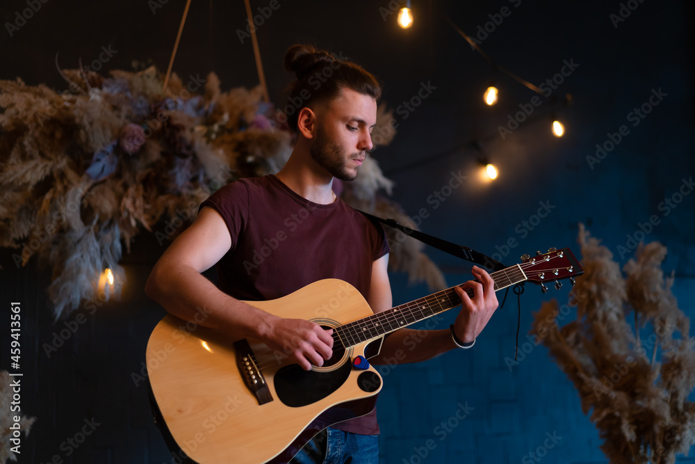 Obraz premium Male musician playing acoustic guitar. Guitarist plays classical guitar on stage in concert