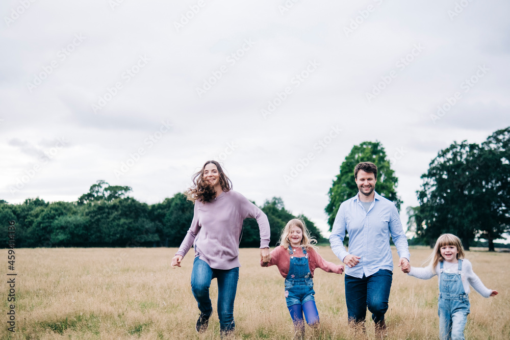 Happy family holding hands while running on meadow Happy family holding hands while running on meadow