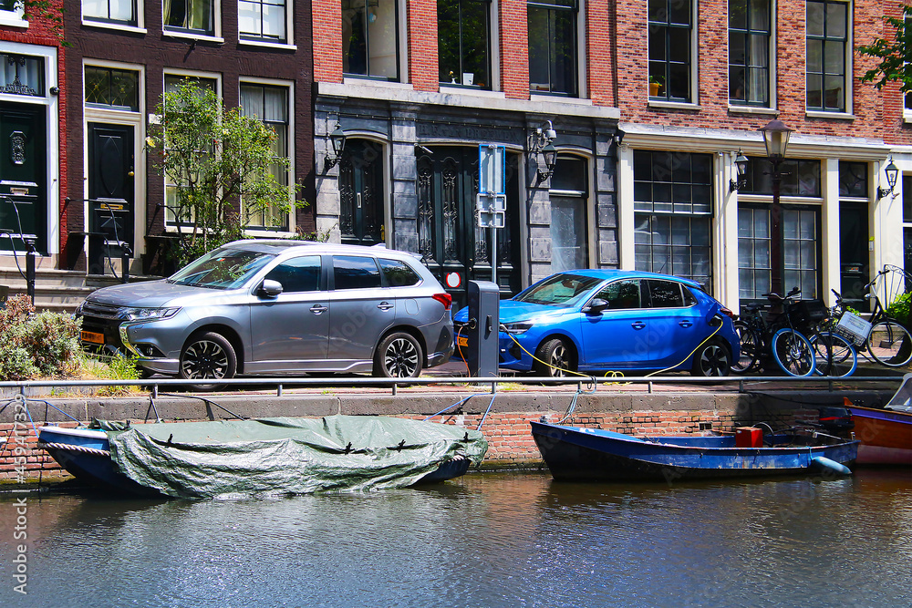 Charging station for electric cars at a canal with boats in the city center of Amsterdam (Netherlands)
