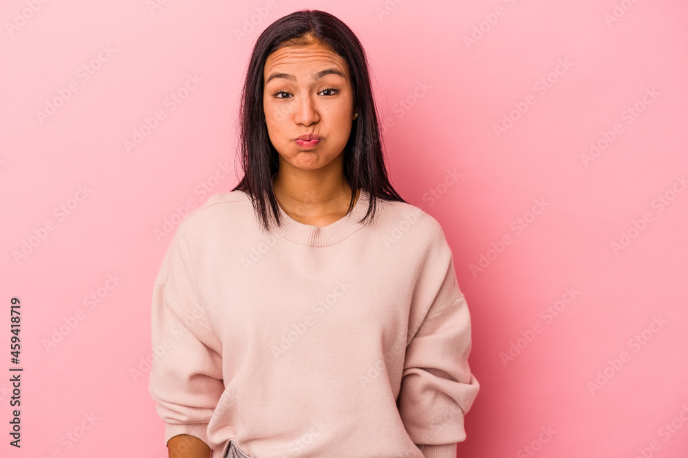Obraz premium Young latin woman isolated on pink background blows cheeks, has tired expression. Facial expression concept.