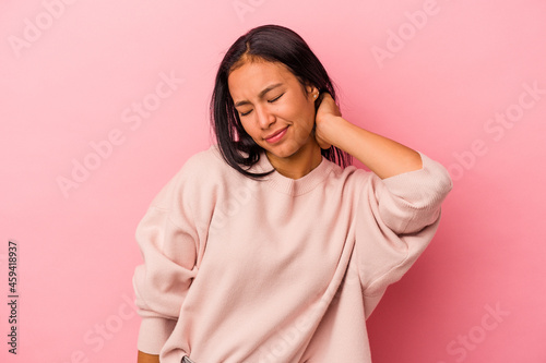 Young latin woman isolated on pink background  having a neck pain due to stress, massaging and touching it with hand. © Asier