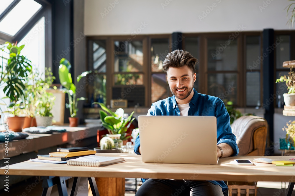 Happy businessman working on laptop at desk in office Happy businessman working on laptop at desk in office