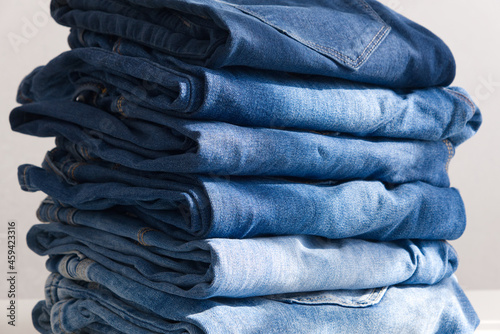 a pile of blue jeans on a light background. Sunlight. Close up (ID: 459423316)