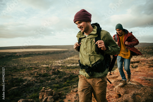 Caucasian male walking hiking in mountain with backpack smiling bonding with friends