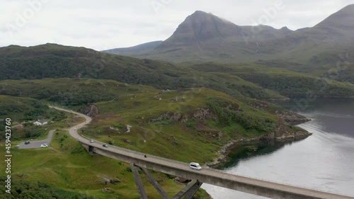 Wide revealing drone shot of the Kylesku Bridge in north-west Scotland that crosses the Loch a' Chàirn Bhàin in Sutherland, with mountains in the distance photo