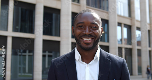 Fotografie Handsome young black businessman smartly dressed looking at camera standing outd