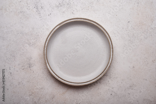 Empty ceramic plate on light concrete table background. Copy space. Menu recipe concept. Top view. Flat lay