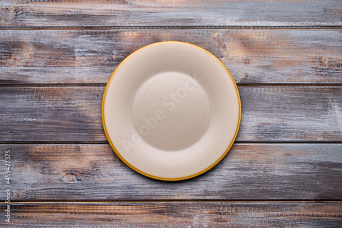 Light empty plate with brown edge on from boards wooden background, top view. Copy space. Menu recipe concept