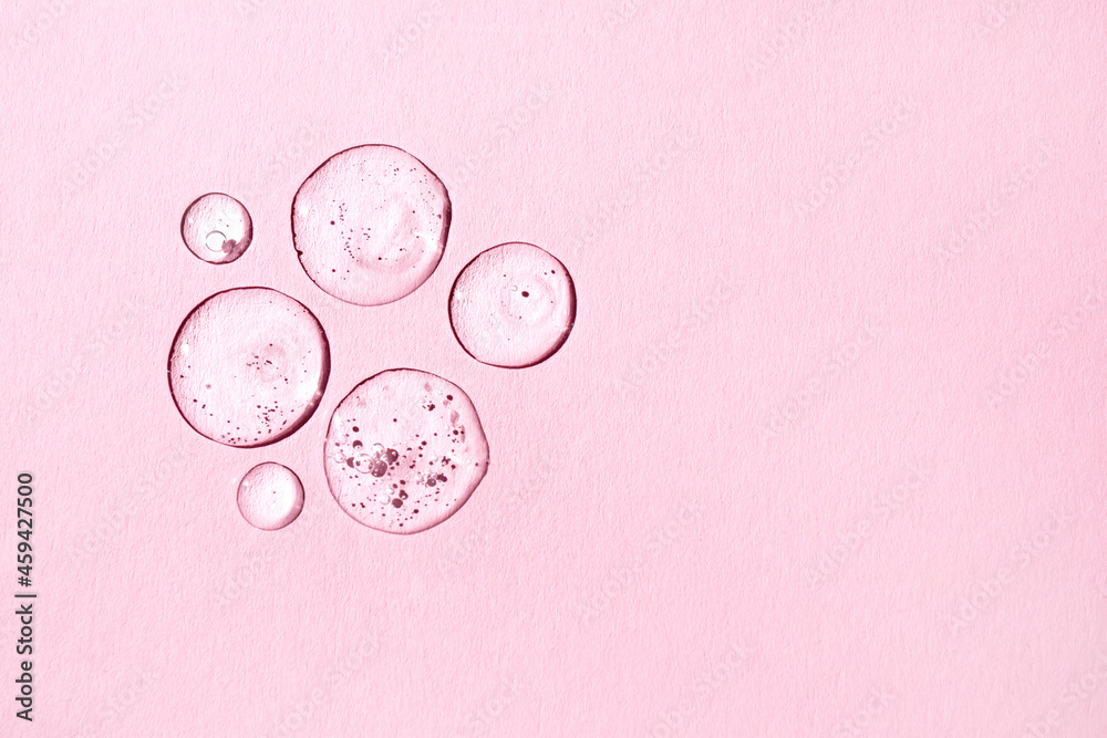 Serum drops on a pink background. Top view, place for text. Cosmetic product.