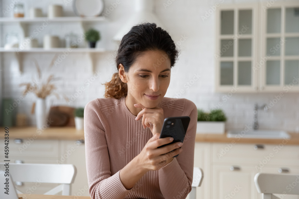 Smiling millennial female look at smartphone screen text message online on device. Happy young Caucasian woman sue cellphone browse wireless internet or talk on video call. Technology concept. Smiling millennial female look at smartphone screen text message online on device. Happy young Caucasian woman sue cellphone browse wireless internet or talk on video call. Technology concept.