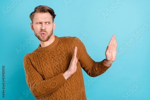 Photo of unhappy disgusted young man look hold hands empty space refuse isolated on blue color background