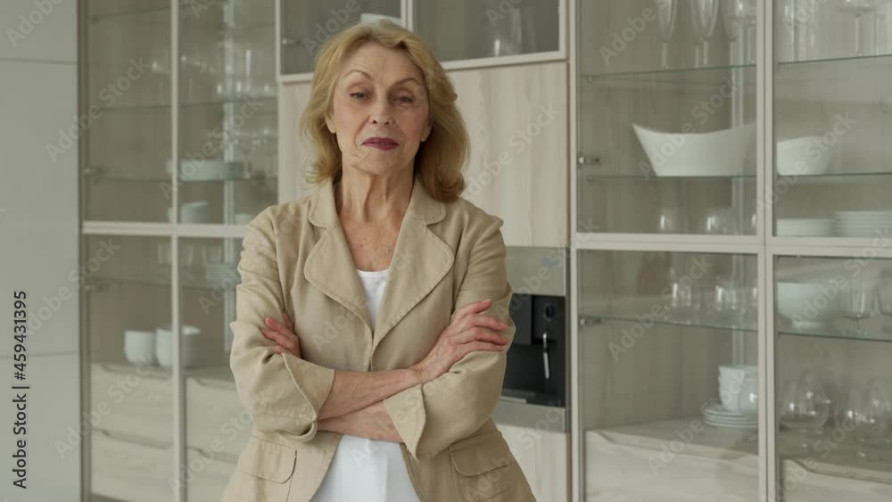 Happy pensioner, resting at home, smiling at the camera, posing against the background of the kitchen Happy pensioner, resting at home, smiling at the camera, posing against the background of the kitchen