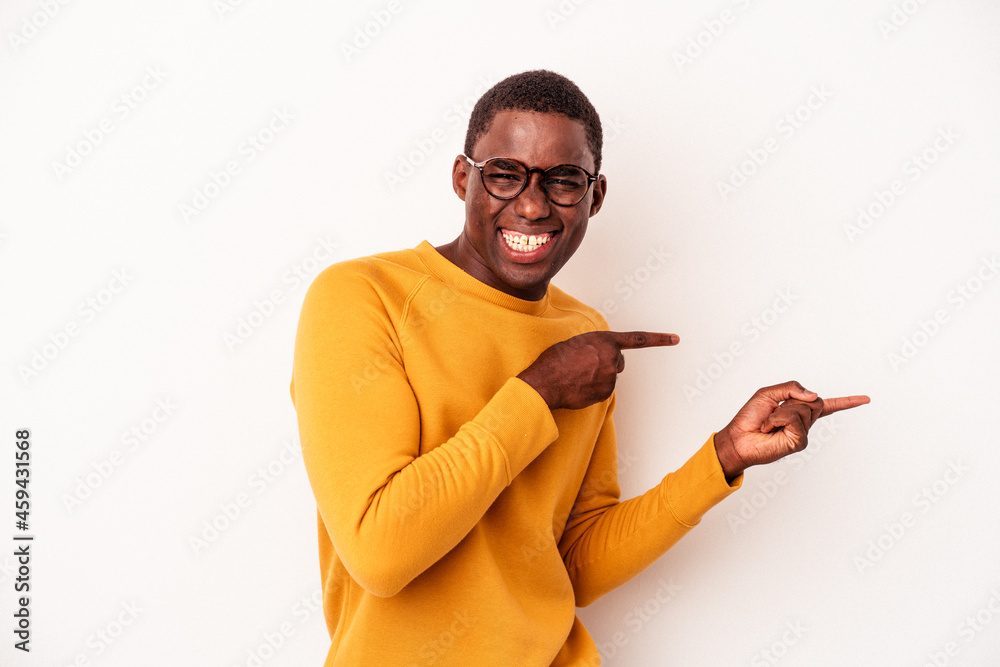 Young African American man isolated on white background excited pointing with forefingers away. Young African American man isolated on white background excited pointing with forefingers away.