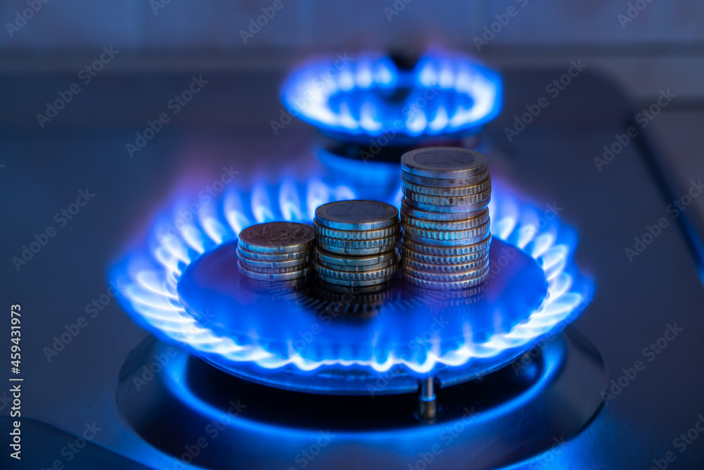 Gas stove lit, with stacks of coins above it. Increase in gas costs and tariffs.
 - obrazy, fototapety, plakaty 