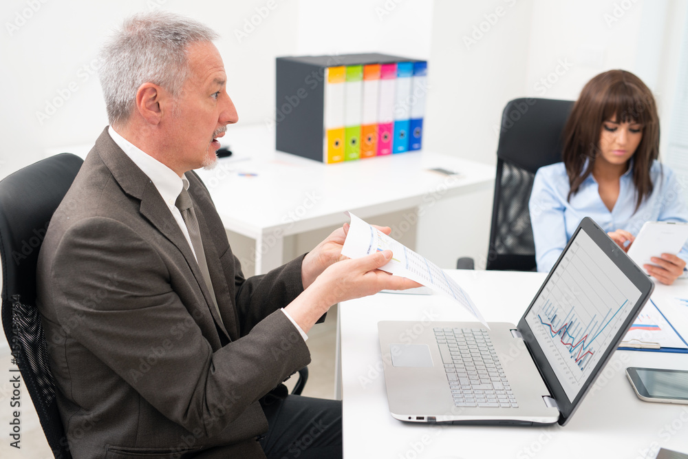 Angry businessman complaining on a document during a meeting Angry businessman complaining on a document during a meeting