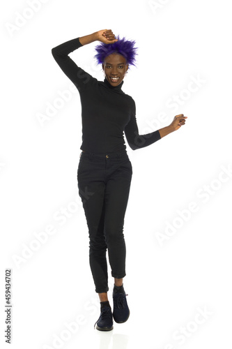 Happy Black Woman Is Dancing With Arms Raised, Front View. Full Length.