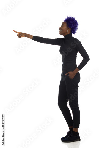 Laughing Young Black Woman Is Standing And Pointing. Side View. Full Length, Isolated.