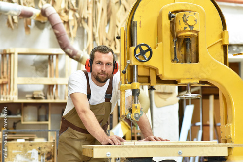 portrait of a carpenter in work clothes and hearing protection in the workshop of a carpenter's shop