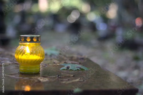 Canvas Print A yellow candle (snitch) on a tombstone, in a cemetery during the day