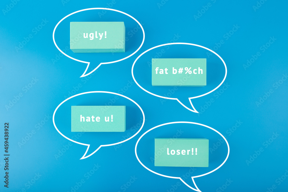 Creative cyberbullying concept. Minimal flat lay with negative, insulting messages in speech bubbles on blue background. Creative cyberbullying concept. Minimal flat lay with negative, insulting messages in speech bubbles on blue background.