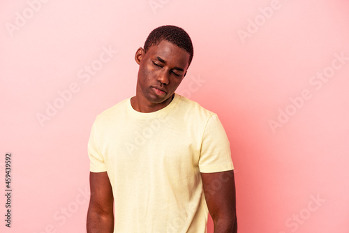 Young African American man isolated on pink background shrugs shoulders and open eyes confused.
