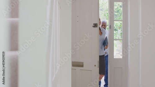 Female realtor opening front door and showing couple around inside of potential new house or apartment - shot in slow motion photo