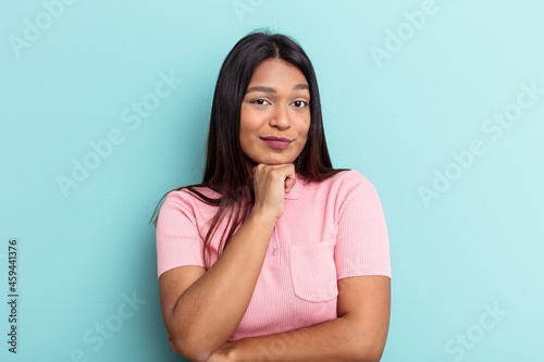 Young Venezuelan woman isolated on blue background suspicious  uncertain  examining you.