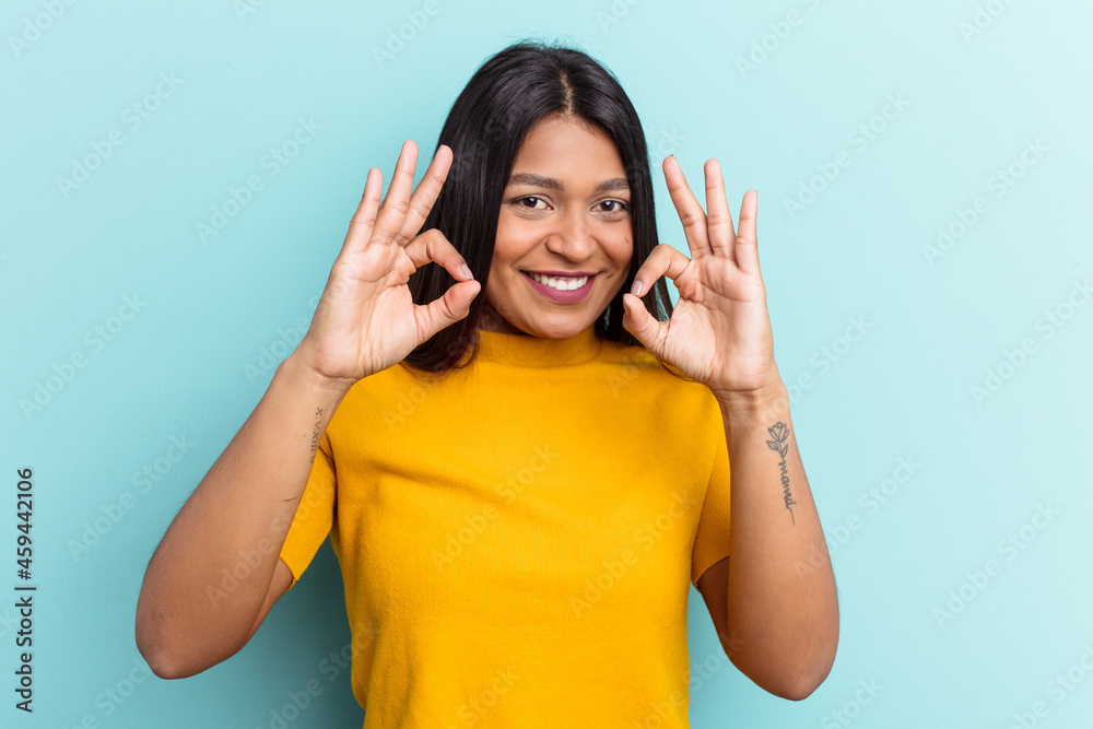 Young Venezuelan woman isolated on blue background cheerful and confident showing ok gesture. Young Venezuelan woman isolated on blue background cheerful and confident showing ok gesture.