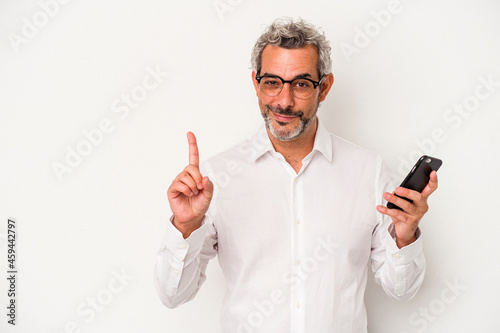 Middle age caucasian business man holding a mobile phone isolated on white background showing number one with finger.