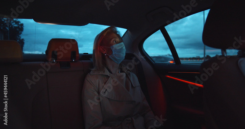 Portrait of woman wearing medical sterile mask in taxi car on backseat © nimito