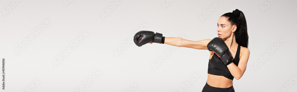 brunette young sportswoman in boxing gloves working out isolated on grey, banner brunette young sportswoman in boxing gloves working out isolated on grey, banner