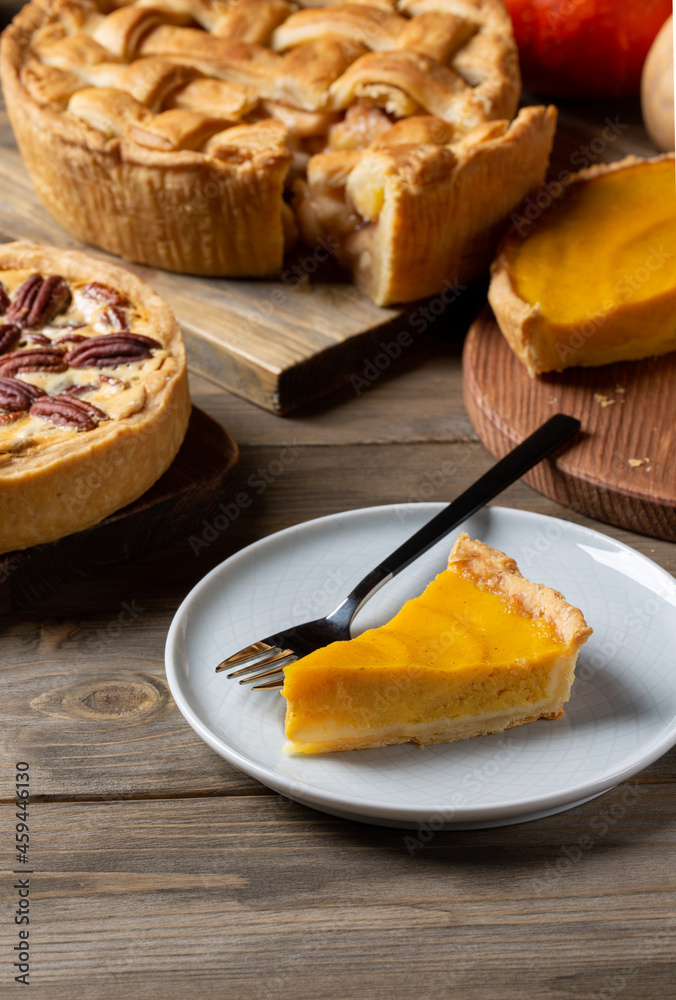 Three homemade autumn pies on wooden background. Traditional American desserts. Pies with pumpkin, apple and pecan for Thanksgiving day.