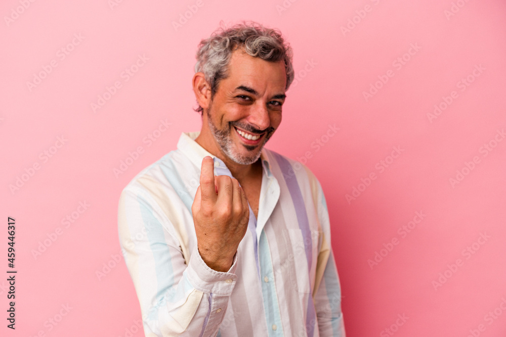 Middle age caucasian man isolated on pink background pointing with finger at you as if inviting come closer. Middle age caucasian man isolated on pink background pointing with finger at you as if inviting come closer.