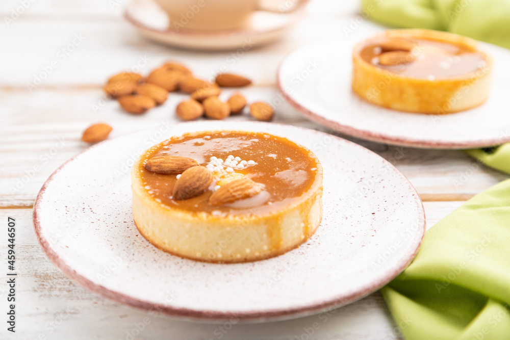 Sweet tartlets with almonds and caramel cream with cup of coffee on a white wooden background. side view, selective focus.