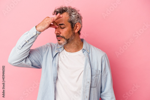 Middle age caucasian man isolated on pink background having a head ache, touching front of the face.